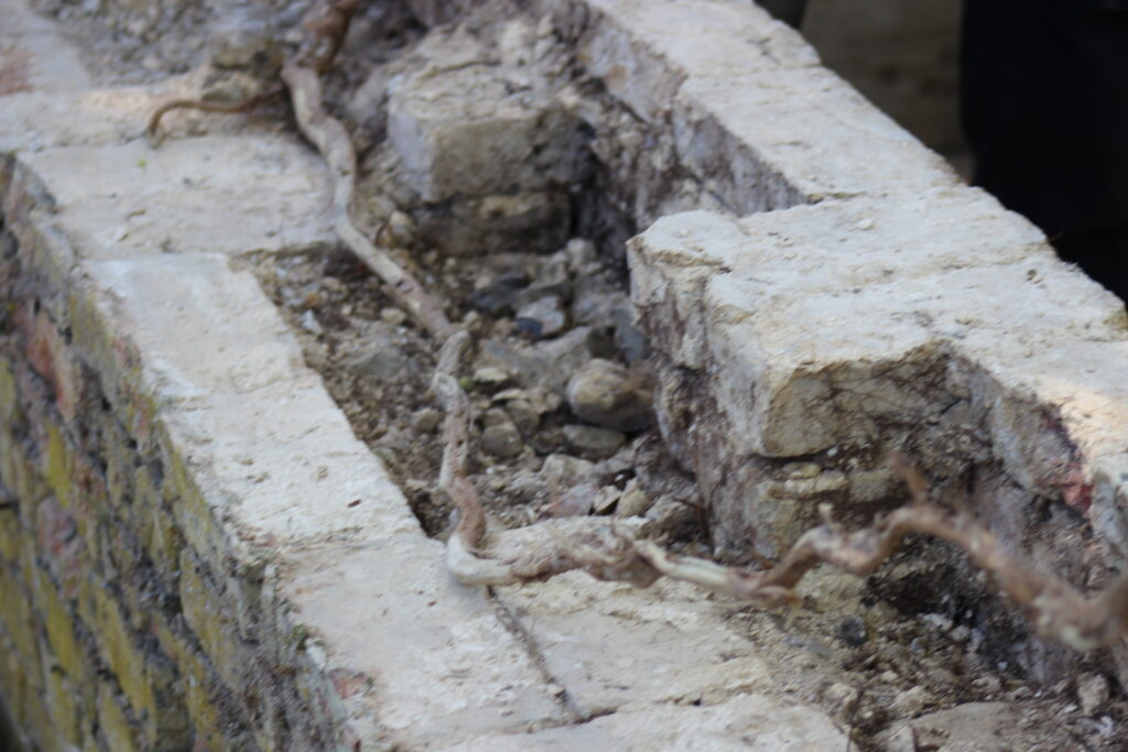 Close-up of crumbled concrete and exposed steel reinforcement in a rubble pile at a construction site.